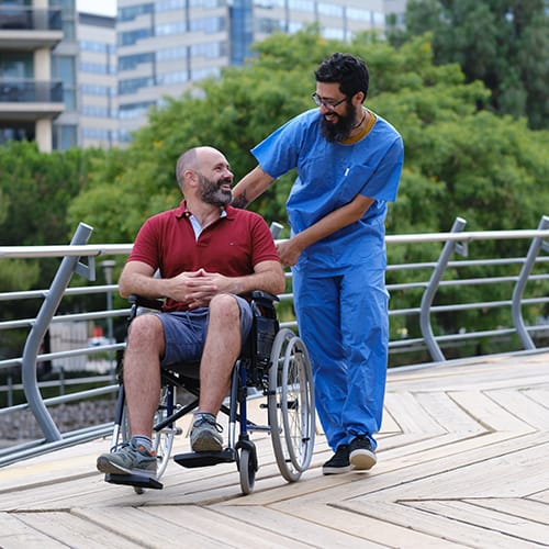 Physiotherapist assisting a patient in a wheelchair outdoors – MSc Rehabilitation course in UK for advanced healthcare studies.