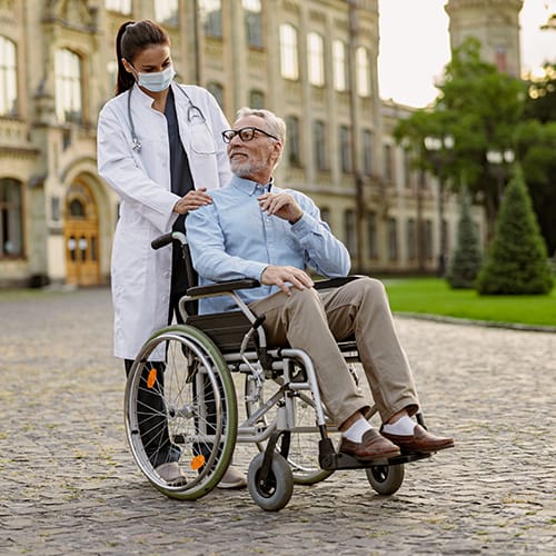 graduate certificate in gerontology and Chronic Illness & Chronic Illness graduate supporting an elderly patient in a wheelchair outdoors