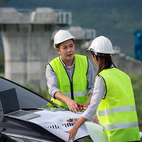 Two engineering students reviewing construction plans outdoors while pursuing MSc Transport Engineering and Planning abroad.