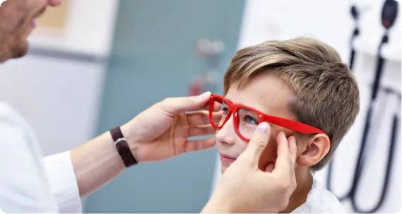 Bachelor of Optometry student helping a child with eyeglasses during vision care practice.
